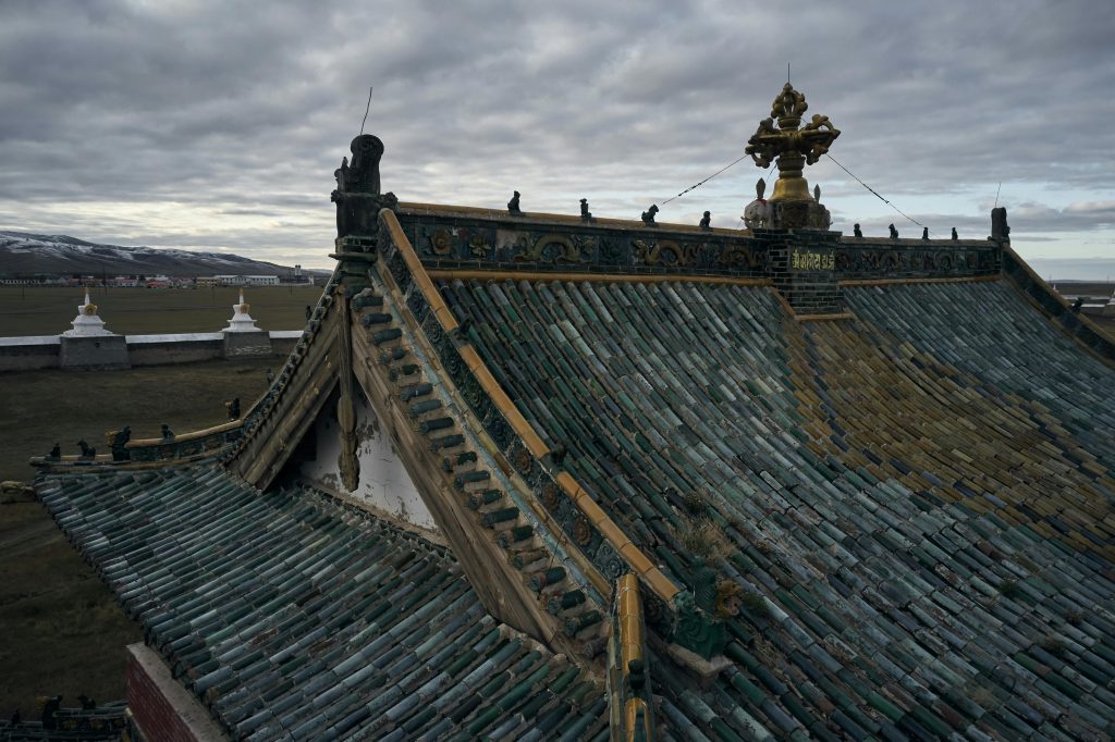 From above of ancient Erdene Zuu Buddhist monastery with tiled roof and decorative roof elements under overcast sky in evening